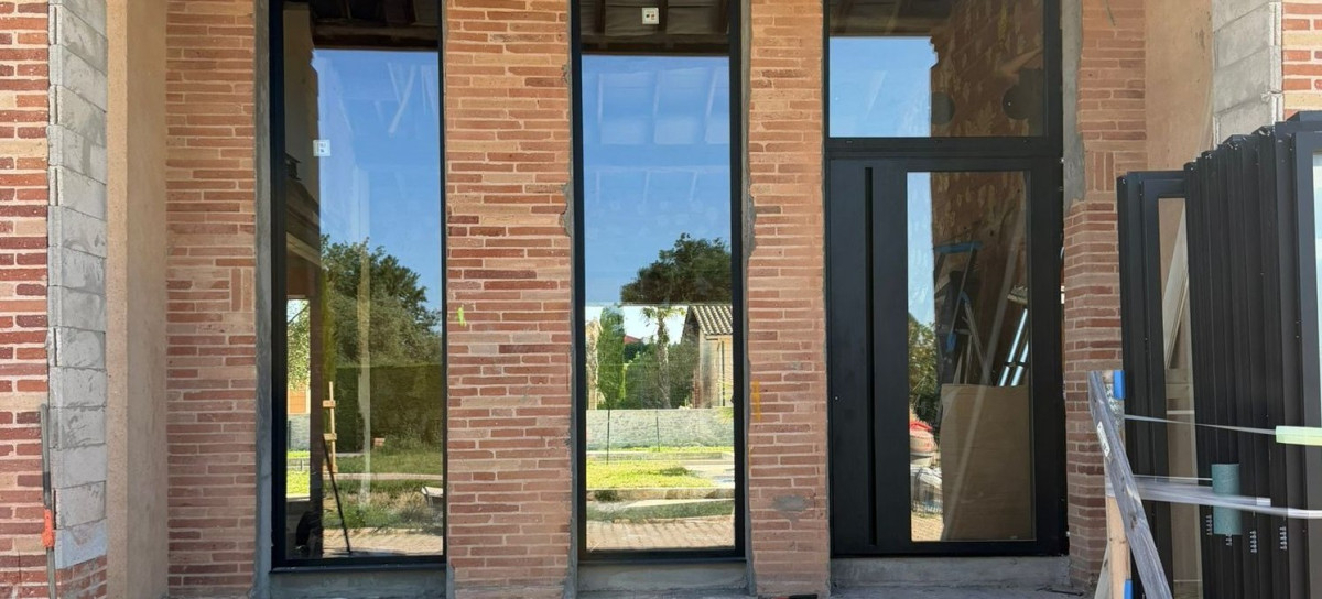 Baies vitrées aluminium noires sur une façade en briques